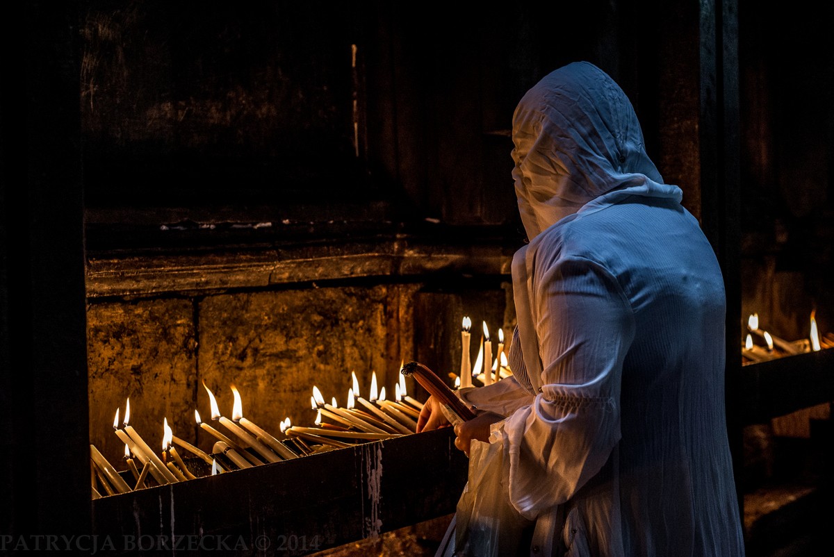 Bazylika Grobu Świętego w Jerozolimie. Kobieta chrześcijańska zapala świece, które mają być złożone w hołdzie Jezusowi Chrystusowi. 